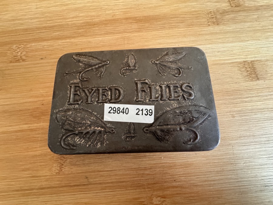 Fliegendose aus Schwarzblech,  Eyed Flies, in Schottland Anfangs des 20. Jahrhunderts hergestellt, Prägung eines Fliegen- Reliefs im Deckel, mit 8 fängigen Lachsfliegen